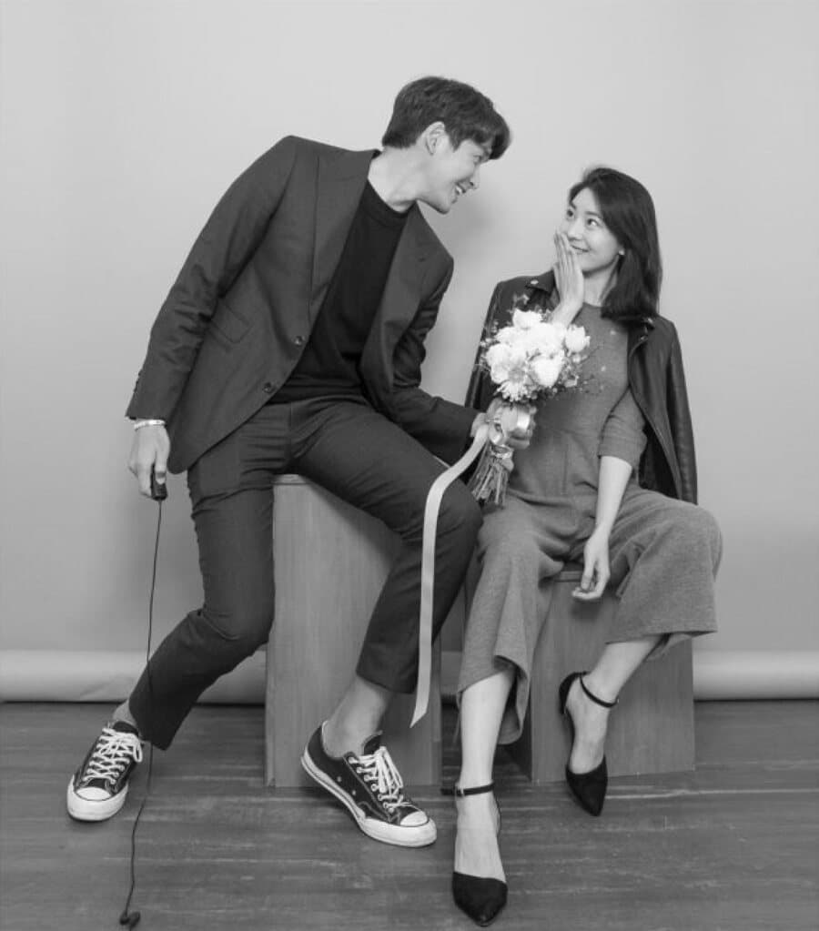 Couple seated on a block, one holding flowers, black and white